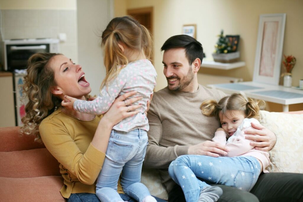 Woman expressing love by playing and laughing with her daughters and spouse