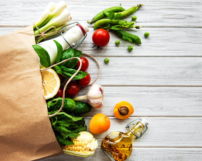 Brown paper shopping bag filled with fresh vegetables and natural oils