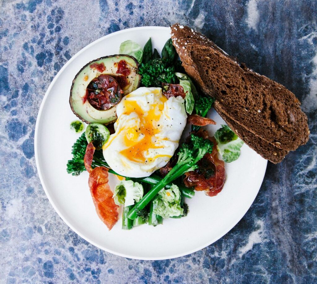 Plate with egg, avocado, vegetables and bread