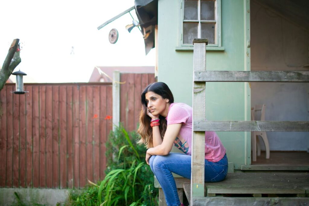 Woman sitting on her back porch worrying and unhappy