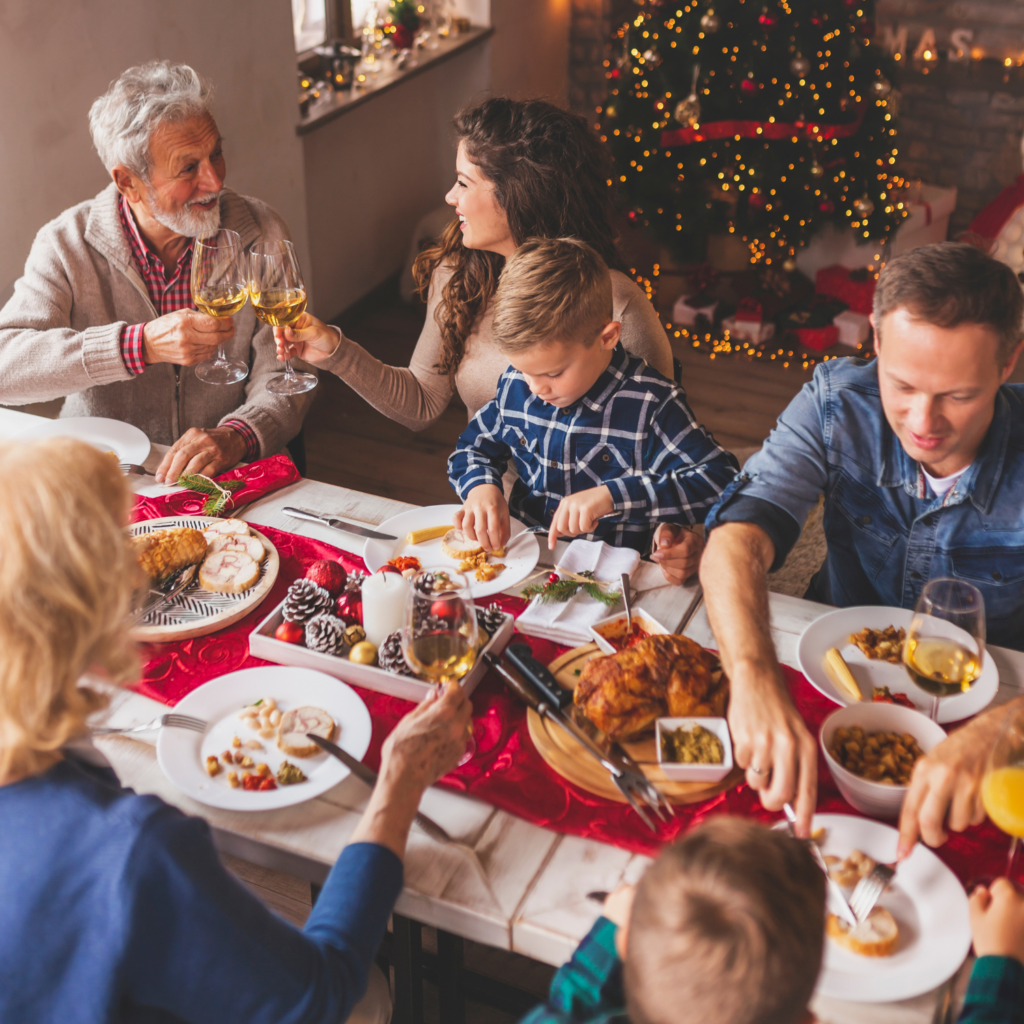 A family gathered around the table, enjoying a festive Christmas dinner together, highlighting the importance of sharing the load during holiday self-care for moms.