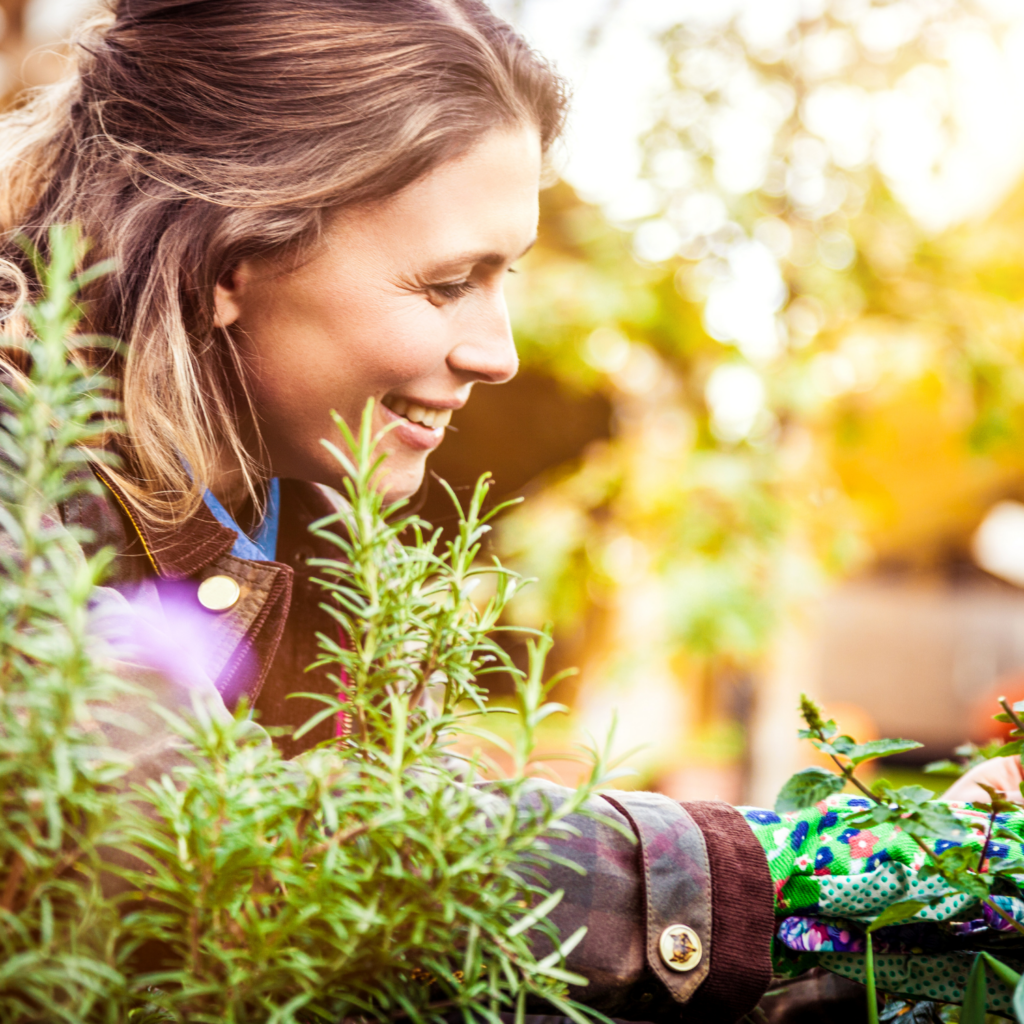 A woman smiling and gardening on a sunny day, showing how detox can improve energy and well-being for moms in menopause.