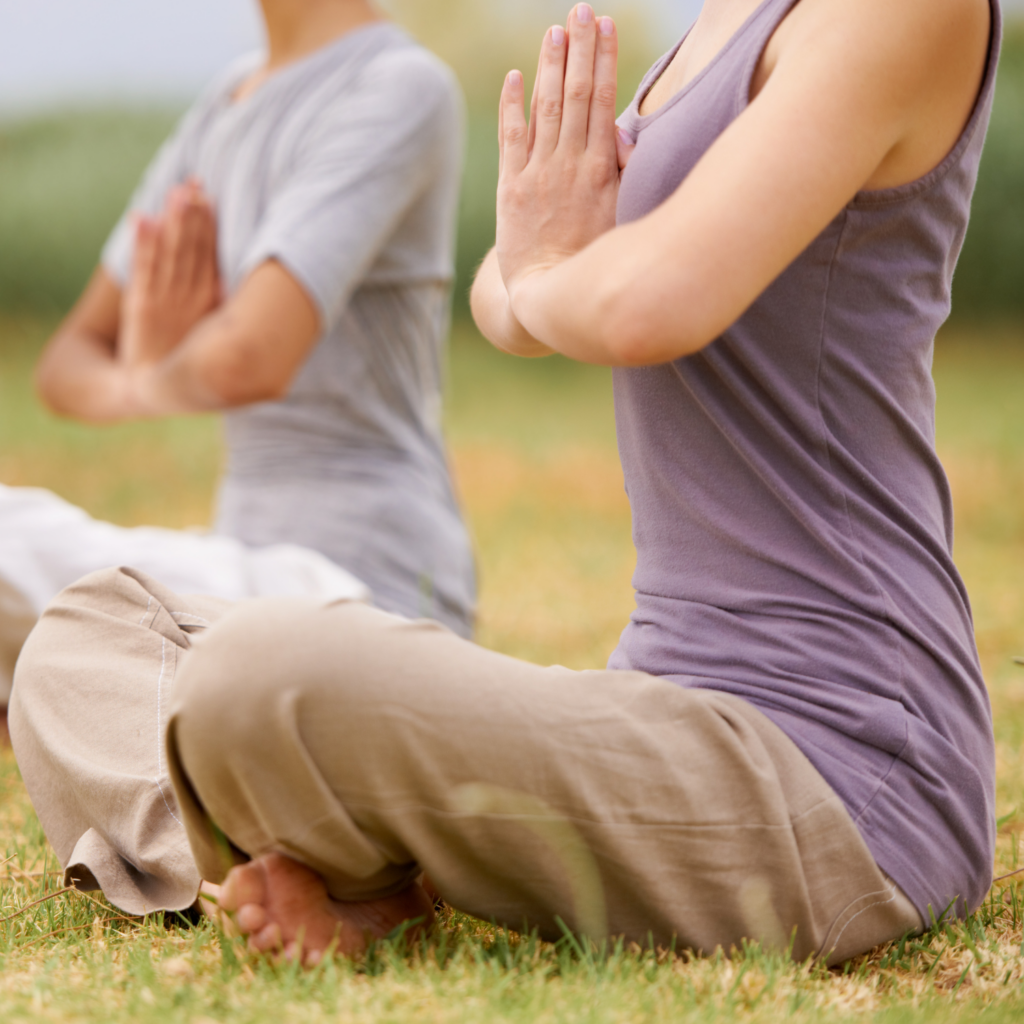 A woman practicing yoga outdoors, using mindfulness and movement to reduce stress and improve cardiovascular health.