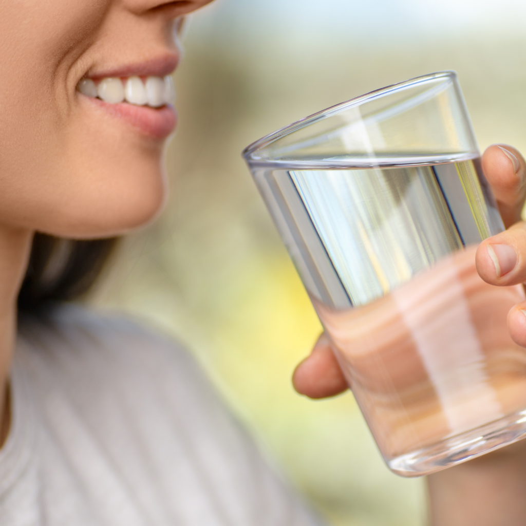 A middle-aged woman drinking water, highlighting the importance of hydration for overall health during menopause.