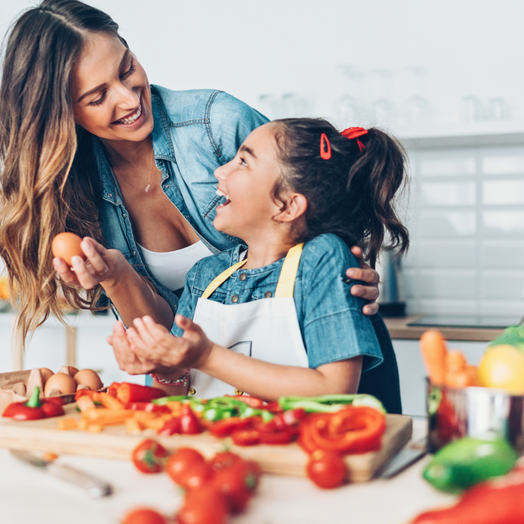 Smiling mom and daughter preparing a healthy meal together, representing nourishing habits for midlife hormone balance